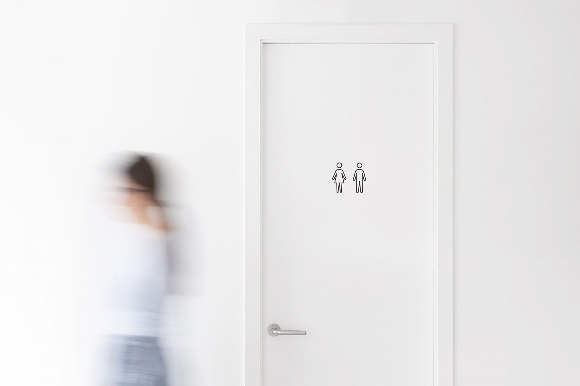 Student walking pass the toilet where our visual identity is displayed for Condé Nast College of Fashion